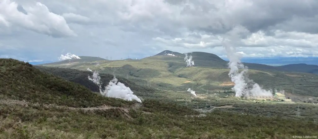 Eine weite Steppe in Kenia. Aus mehreren Öffnungen in der Erde strömt Dampf. Heiße Quelle sind in der Region sehr verbreitet. Sie dienen der Stromgenierung. Die grüne Landschaft dampft. Darüber er blaue Himmel.